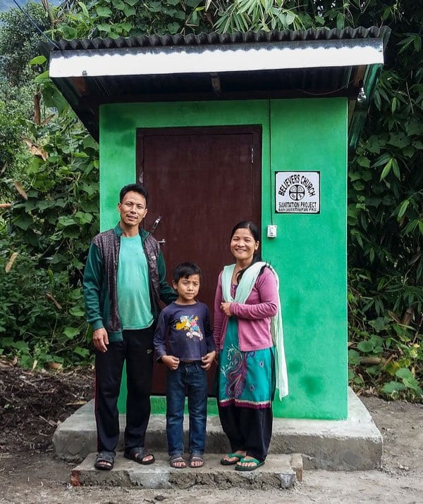 A family in front of a GFA-provided outdoor toilet facility