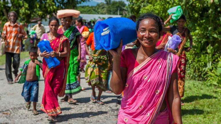 Crowd and woman walking away happily after receiving the gift of mosquito nets