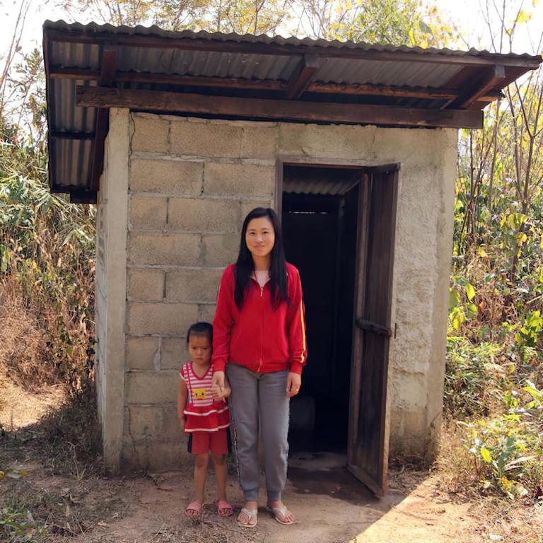 Woman and her child in Laos in front of an outdoor toilet