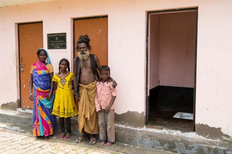 Family in front of outdoor toilets built through GFA World donations