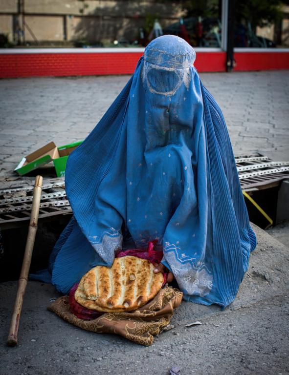 A widow begs on a busy road