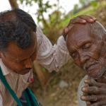National missionary worker prays for elderly man