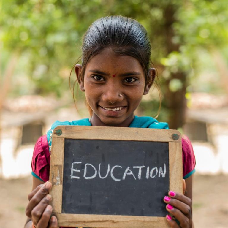 Young girl holding a chalkboard with Education written on it