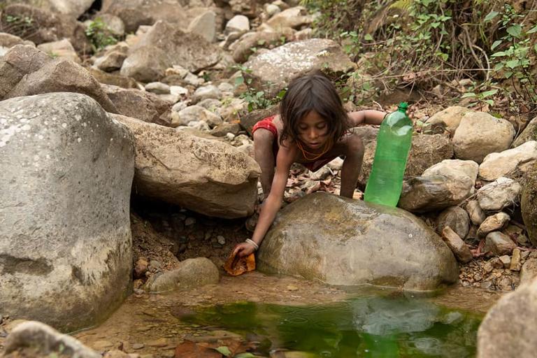Small boy collecting unclean water from an open water source
