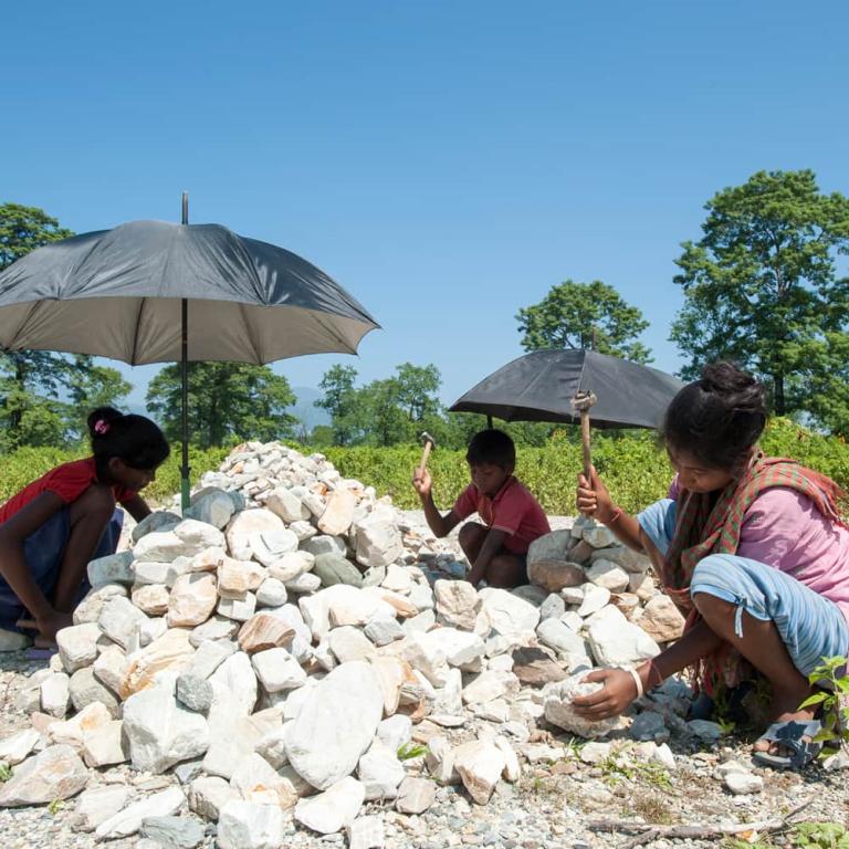 Children with their mother collects stones to help earn a little money for their family