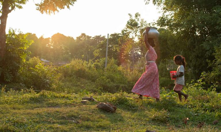 A mother and her child walk long distances to acquire water that is often times unclean and contaminated