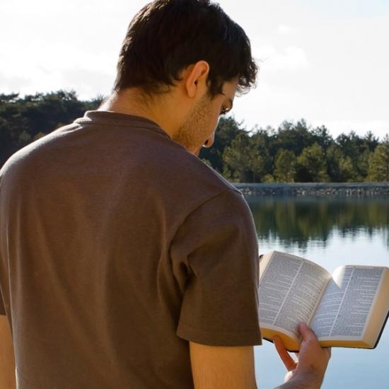 guy-reading-bible-lake_credit-Shutterstock.com