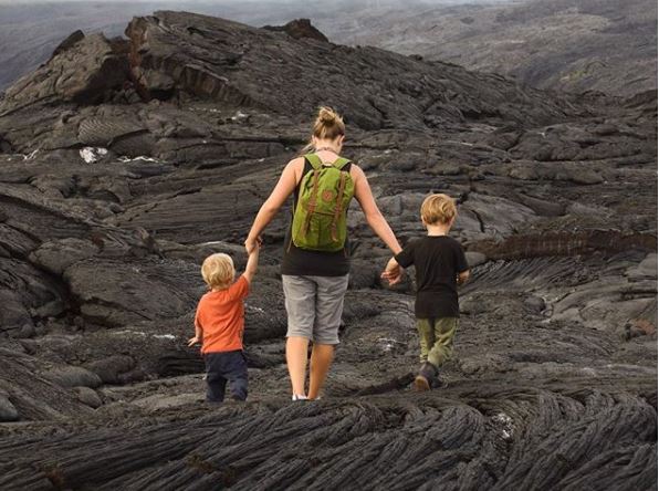 Mom and two boys walk across lava fields