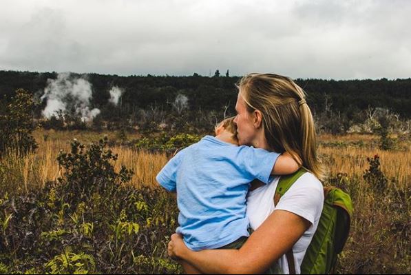 Mother and son watching volcanic steam rise from the scarred earth