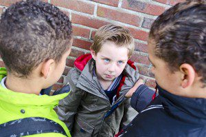 Two bully boys beating up a small boy