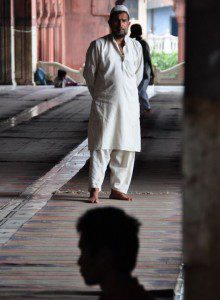 muslim man looks over a meditator at Jama Masjid, India