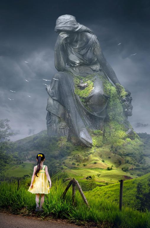 A little girl looking over at a huge monument statue of a weeping lady