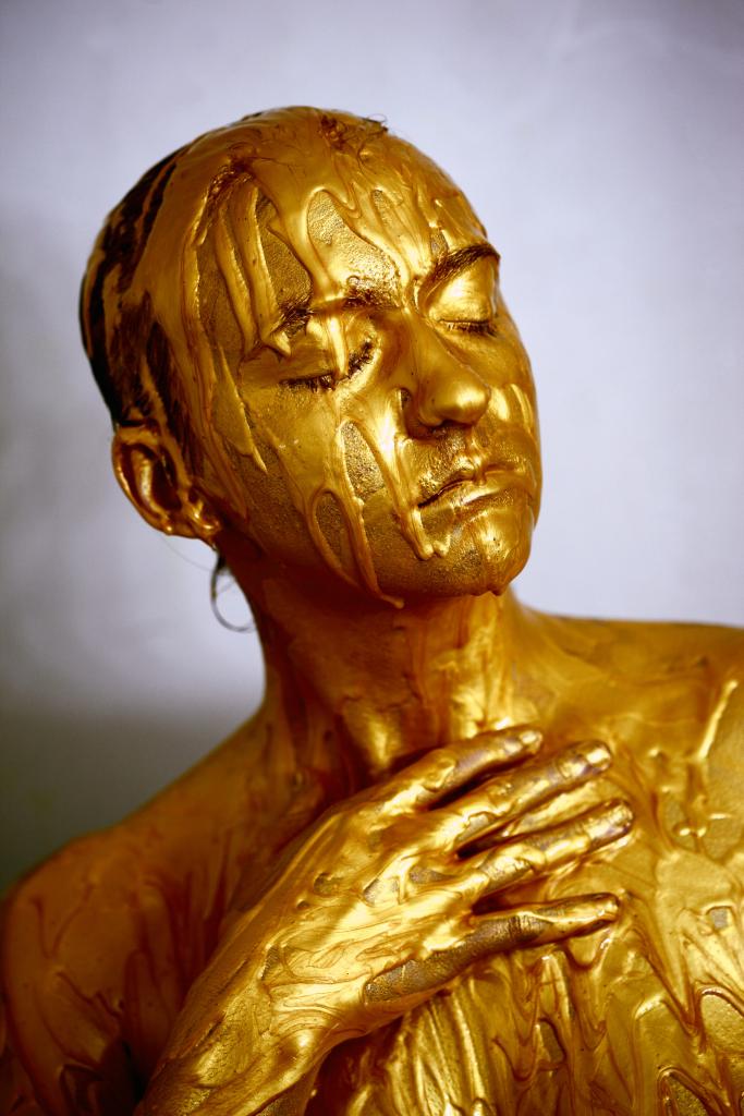 A woman drenched in gold paint, like a melting statue