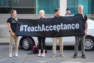 people holding black and white banner reading -- teach acceptance