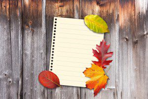 open spiral-bound notebook with brilliantly colored autumn leaves scattered along the edges