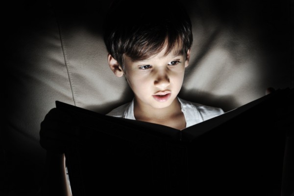 Kid reading book, light in darkness