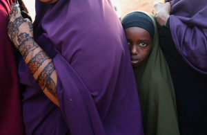 A girl lines up to enter a bus heading for Nairobi at the Somali-Kenyan border, while police search the bus for weapons. Image by Goran Tomasevic/Reuters