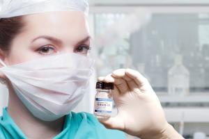 Woman doctor with mask holding vaccine vial