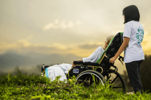 Woman taking a man in a wheelchair to look at the beauty of creation