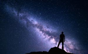 A person ponders the galaxy appearing in the night sky.