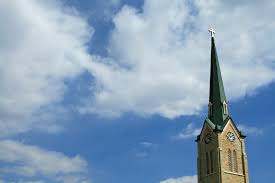 A church steeple against a blue sky with clouds.