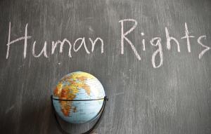 A globe of the world stands before a chalkboard on which "Human Rights" is written.