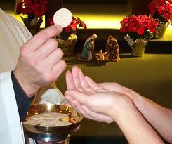 A Communion minister places the consecrated host into waiting hands.