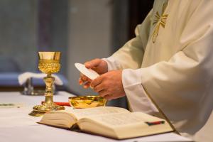 A priest holds the large host that he will break, an important symbol in the Communion Rite.