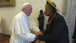 Pope Francis and Raoni Metuktire grasping each other's hands.