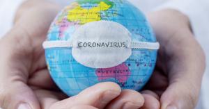 Two hands hold a globe of the world on which is placed a bandage with the word "coronavirus."