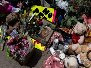 The site where George Floyd was killed is adorned with flowers, signs, and a picture of Floyd.